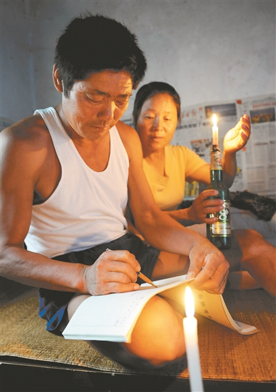 王继才和妻子在烛光下填写巡逻日记。
